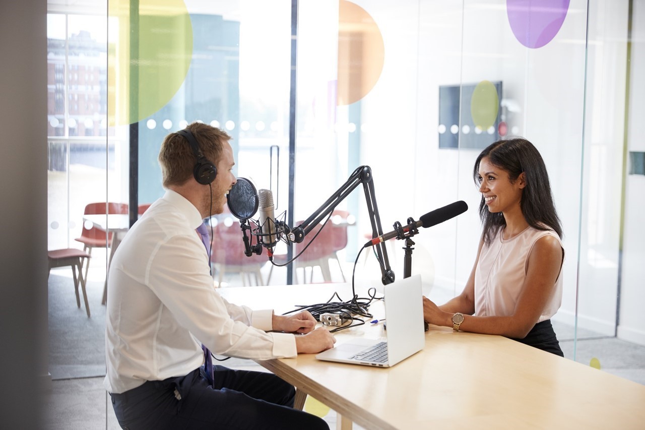 Man and woman interview each other with microphones for podcast