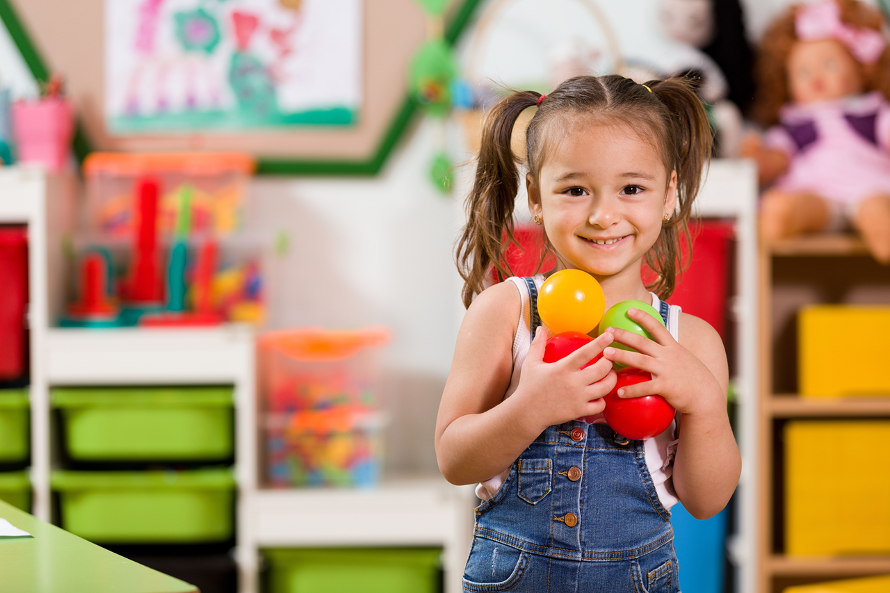 Young girl smiling and holding learning toys