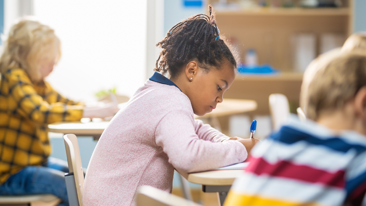 Young student writing at her desk.